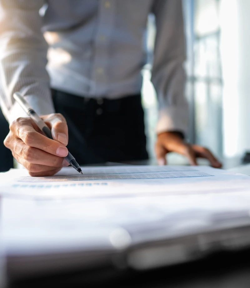 Image d'un homme d'affaire avec un stylo à la main écrivant sur des feuilles sur un bureau
